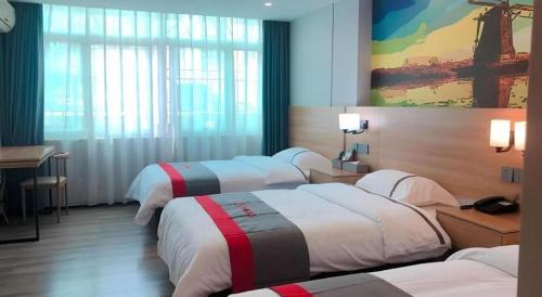 a hotel room with four beds and a desk at Jun Hotel Guangdong Zhanjiang Xiashan South Railway Station in Zhanjiang