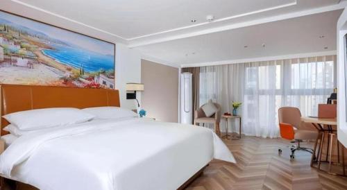 a bedroom with a large white bed and a desk at Vienna Hotel Chengdu Exhibition Center In Time City in Chengdu