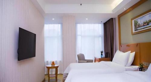 a hotel room with two beds and a flat screen tv at Vienna Hotel Inner Mongolia Tongliao Development Zone in Tongliao