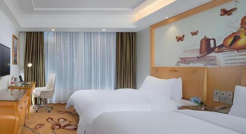 a hotel room with two beds and a desk and a computer at Vienna Hotel Guangdong Zhaoqing Sihui Tianguangxu in Zhaoqing