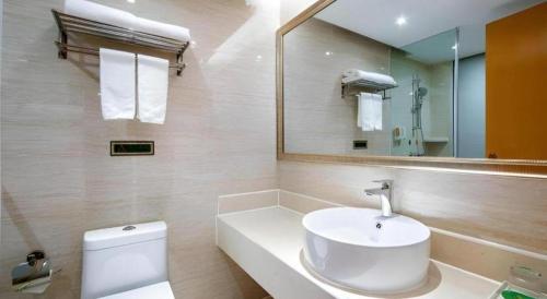 a bathroom with a white sink and a mirror at Vienna Hotel Guangxi Guilin Xing'an in Guilin