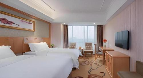 a hotel room with two beds and a television at Vienna Hotel Guangxi Guilin Xing'an in Guilin