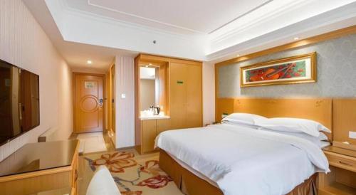 a bedroom with a large bed and a television at Vienna Hotel Guangxi Guilin Xing'an in Guilin