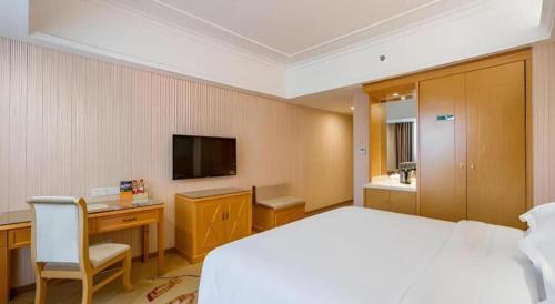 a bedroom with a bed and a desk and a television at Vienna Hotel Guangxi Guilin Xing'an in Guilin