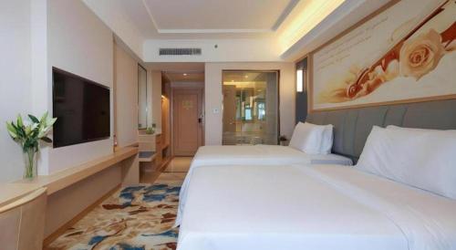 a hotel room with two beds and a flat screen tv at Vienna Hotel Chengdu University of Pertroleum Metro Station in Chengdu