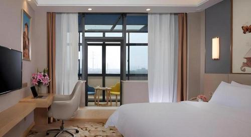 a hotel room with a bed and a desk and a window at Vienna Hotel Jiangsu Zhangjiagang Passenger Terminal Station in Zhangjiagang