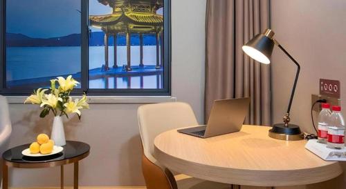 a room with a table with a laptop on it at Vienna Hotel Hangzhou East Railway Station West Square in Hangzhou