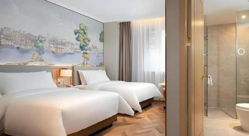 a hotel room with two beds and a bathroom at Vienna Hotel Hangzhou East Railway Station West Square in Hangzhou