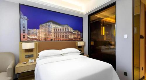 a bedroom with a large white bed and a picture of a building at Vienna Hotel Jiangxi Shangrao High-Speed Railway Station in Shangrao