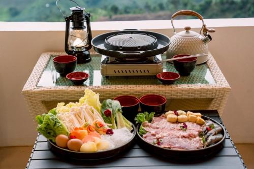 a table with two plates of food and a grill at Nontawa Villa Doichang in Ban Huai Khai