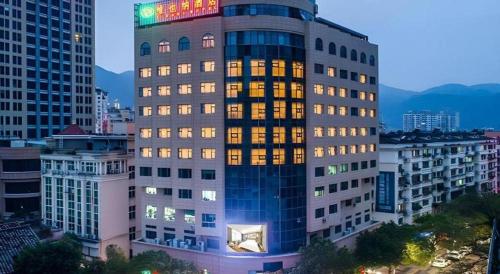 a tall building with lights on in a city at Vienna Hotel Zhejiang Lishui Qingtian Post Building in Lishui