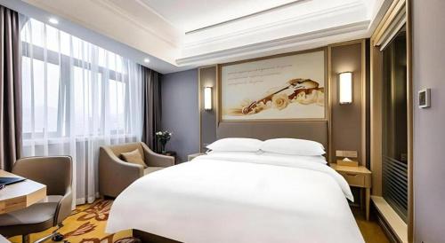 a hotel room with a large white bed and a chair at Vienna Hotel Zhejiang Lishui Qingtian Post Building in Lishui