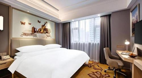 a bedroom with a white bed and a desk and a computer at Vienna Hotel Zhejiang Lishui Qingtian Post Building in Lishui