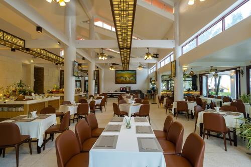 a restaurant with white tables and chairs and windows at Mercury Phu Quoc Resort & Villas in Phu Quoc