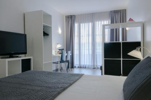 a bedroom with a bed with a television and a desk at Aparthotel Atenea Calabria in Barcelona