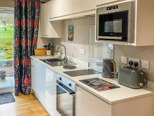 una cocina con fregadero y microondas en Dalnafeidh Beag - Cottage, en Portnacroish