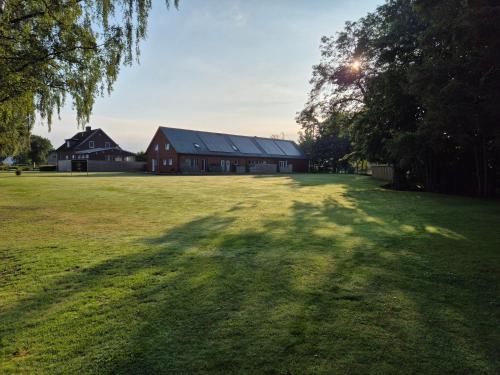 a large grass field with a large red barn at Country Lodge Lärkboet in Laholm