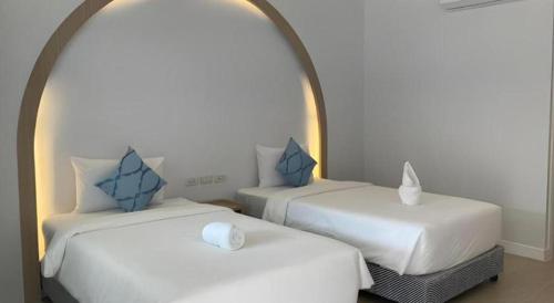 a room with two white beds with blue pillows at Thong Prachok Hotel in Sakon Nakhon