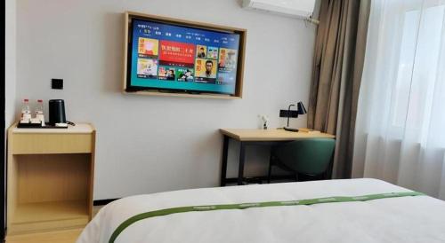 a bedroom with a bed and a tv on the wall at GreenTree Inn Express Qingdao Jiaodong International Airport in Qingdao