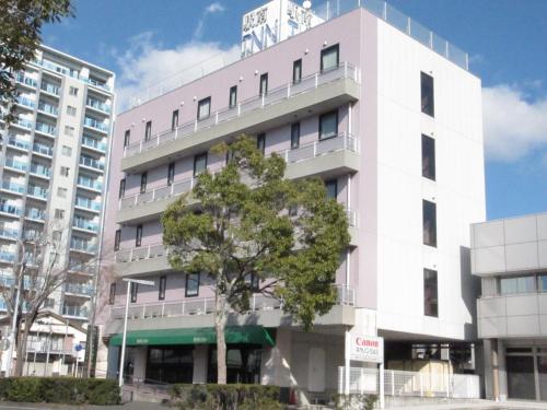a pink building with a tree in front of it at Hotel Kakegawa Hills in Kakegawa