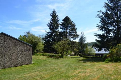 a yard with grass and trees and a building at Village Vacances Yaloer in Villefranche-de-Panat