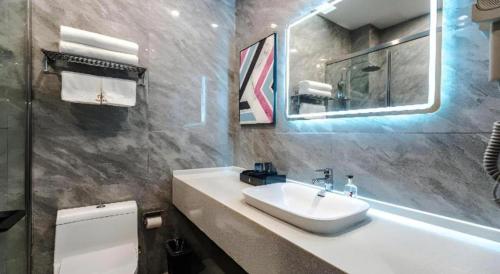 a bathroom with a sink and a mirror and a toilet at Borrman Hotel Changzhi Medical College Wulong Campus High-speed Railway South Station in Changzhi