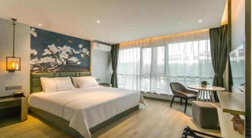 a bedroom with a large white bed and a table at Magnotel Hotel Suzhou Shiquan Street Wangshiyuan in Suzhou