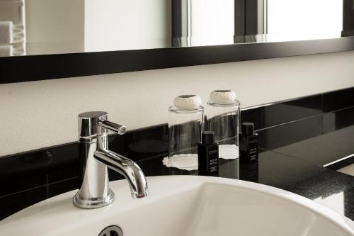 a bathroom sink with a faucet and a mirror at TOWNHOUSE Hotel in Frankfurt/Main