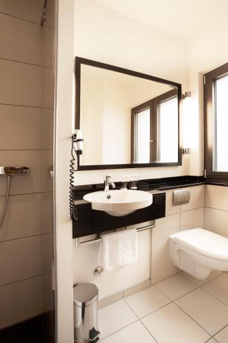 a bathroom with a sink and a mirror and a toilet at TOWNHOUSE Hotel in Frankfurt/Main