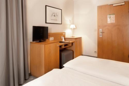 a bedroom with a bed and a desk with a television at TOWNHOUSE Hotel in Frankfurt/Main