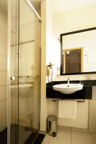 a bathroom with a sink and a glass shower at TOWNHOUSE Hotel in Frankfurt/Main