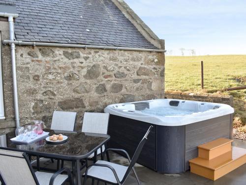 einen Whirlpool auf einer Terrasse mit einem Tisch und Stühlen in der Unterkunft Benwells Holiday Cottage in Maud