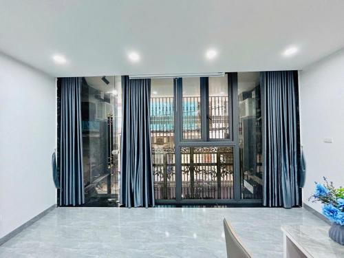 a living room with a large glass door with curtains at Lilo's Homestay West Lake Thuy Khue in Hanoi