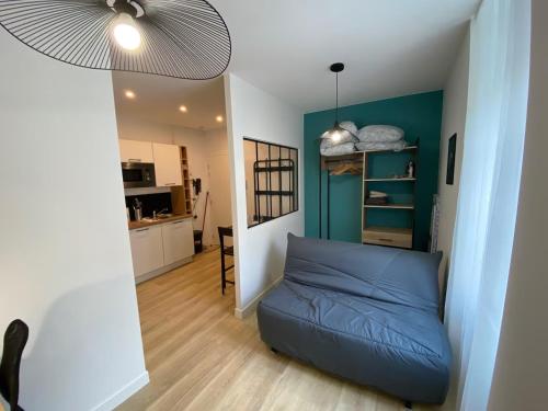 a living room with a blue couch and a kitchen at Logement Neuf Cosy avec Espaces Communs Premium 01 in Belfort