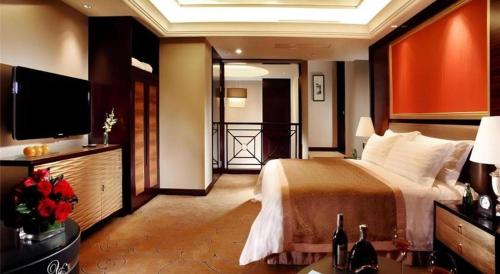 a bedroom with a large bed and a flat screen tv at Royal Tulip Hotel Zhujiajiao Shanghai in Shanghai