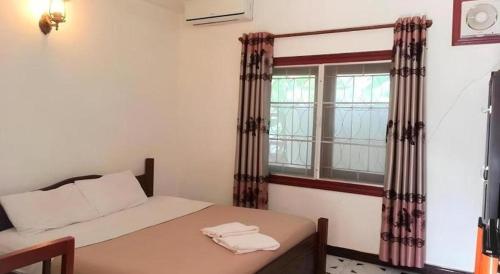 a small bedroom with a bed and a window at Khamsaner Hotel in Vientiane
