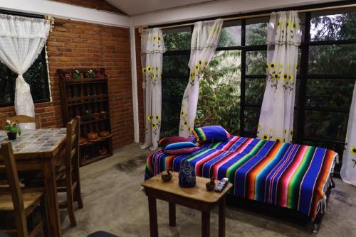 a bedroom with a bed and a table and windows at Find Your Perfect Mountain Retreat at House Sun 