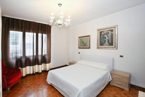 sypialnia z białym łóżkiem i żyrandolem w obiekcie Appartamento Martina C. w mieście Marghera