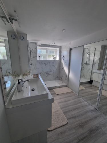 a white bathroom with a sink and a shower at La Villa Bellevue - 8 personnes avec piscine in Buissou