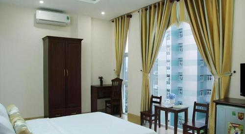 a bedroom with a bed and chairs and a window at Huong Binh Hotel in Da Nang