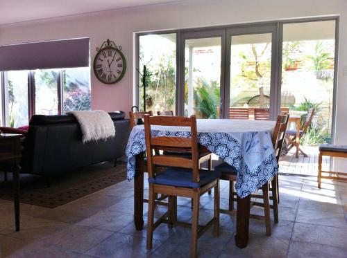 a living room with a table and chairs and a clock at Mt Lawley Garden Apartment in Perth