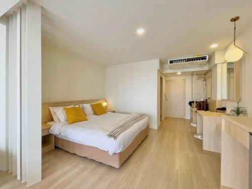 a bedroom with a bed with yellow pillows and a kitchen at Bangsaen Villa Hotel in Si Racha