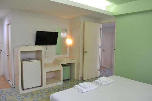 a room with two beds and a desk and a television at Bangsaen Villa Hotel in Si Racha