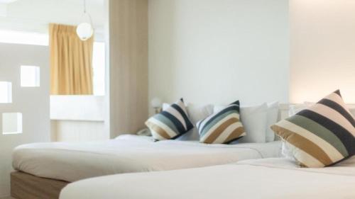 two beds in a room with pillows on them at Bangsaen Villa Hotel in Si Racha