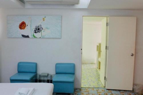 a room with two blue chairs and a painting on the wall at Bangsaen Villa Hotel in Si Racha