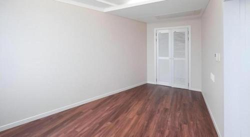 an empty living room with white walls and wood floors at Galaxy Hotel in Jeju