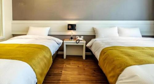 two beds in a room with a table between them at Galaxy Hotel in Jeju