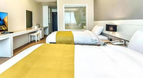 a hotel room with two beds and a mirror at Galaxy Hotel in Jeju