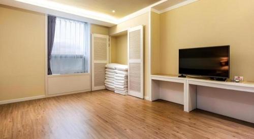 a living room with a flat screen tv and a large window at Galaxy Hotel in Jeju