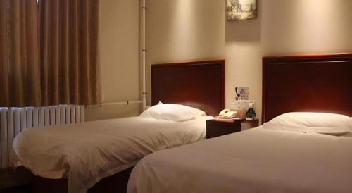 a hotel room with two beds and a telephone at GreenTree Inn Beijing East Yizhuang District Second Kechuang Street Express Hotel in Beijing
